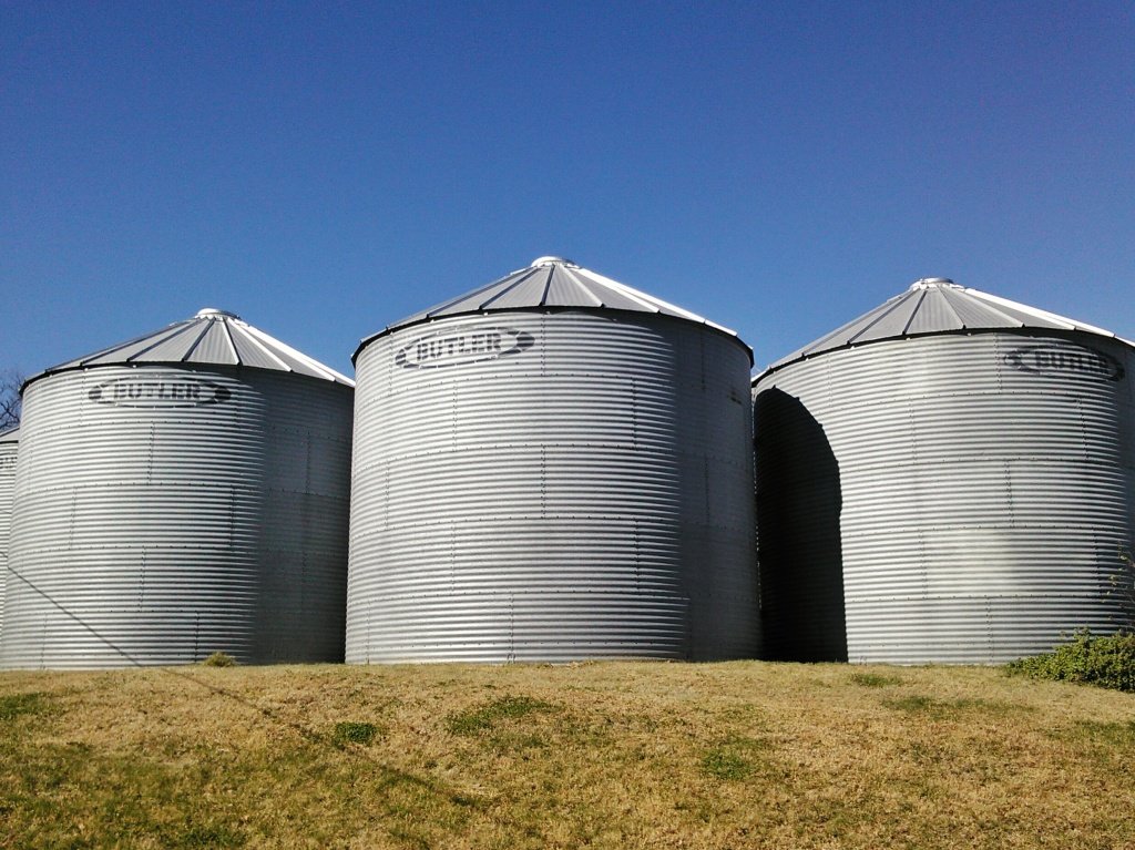 These are grain bins. Unlike a silo, bins are used to store dry feeds like corn or soybeans. Silos on the other hand hold things that are wetter and that you want to ferment. Thanks to my friend Nicole for sending me a photo of their grain bins. Click on this photo to visit her blog!